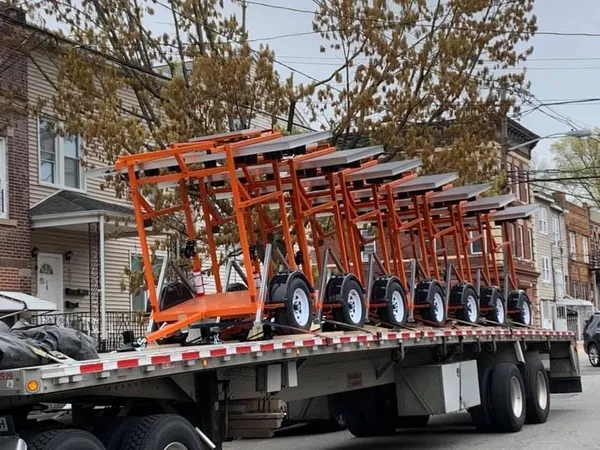 Row of orange arrow board trailers loaded on a flatbed for delivery