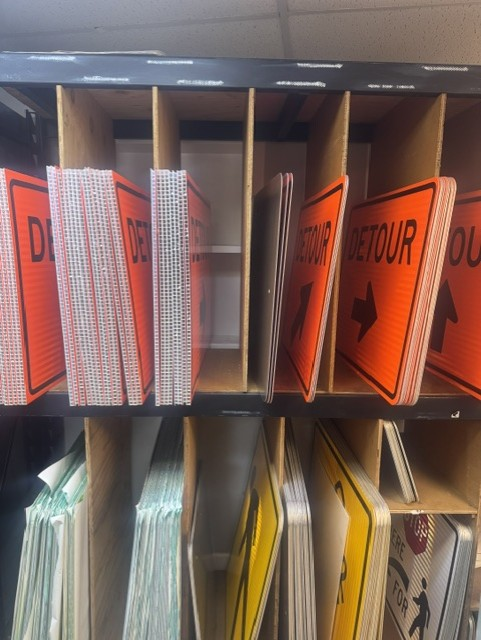 Rack of orange reflective DETOUR arrow signs in the HTC sign shop