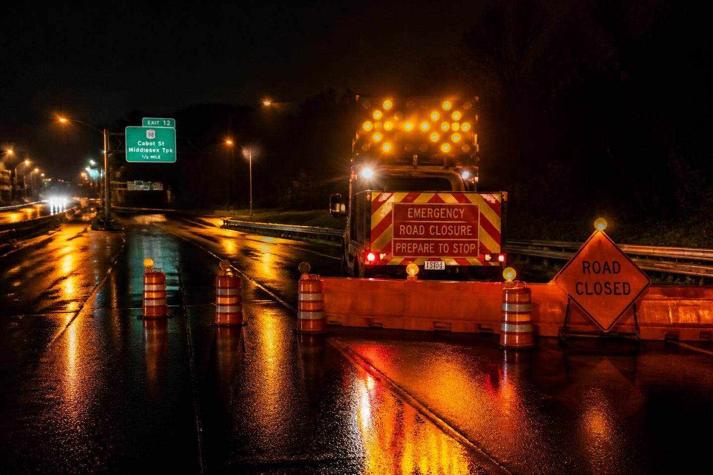 Traffic control truck with amber strobe lights closing a highway lane at night
